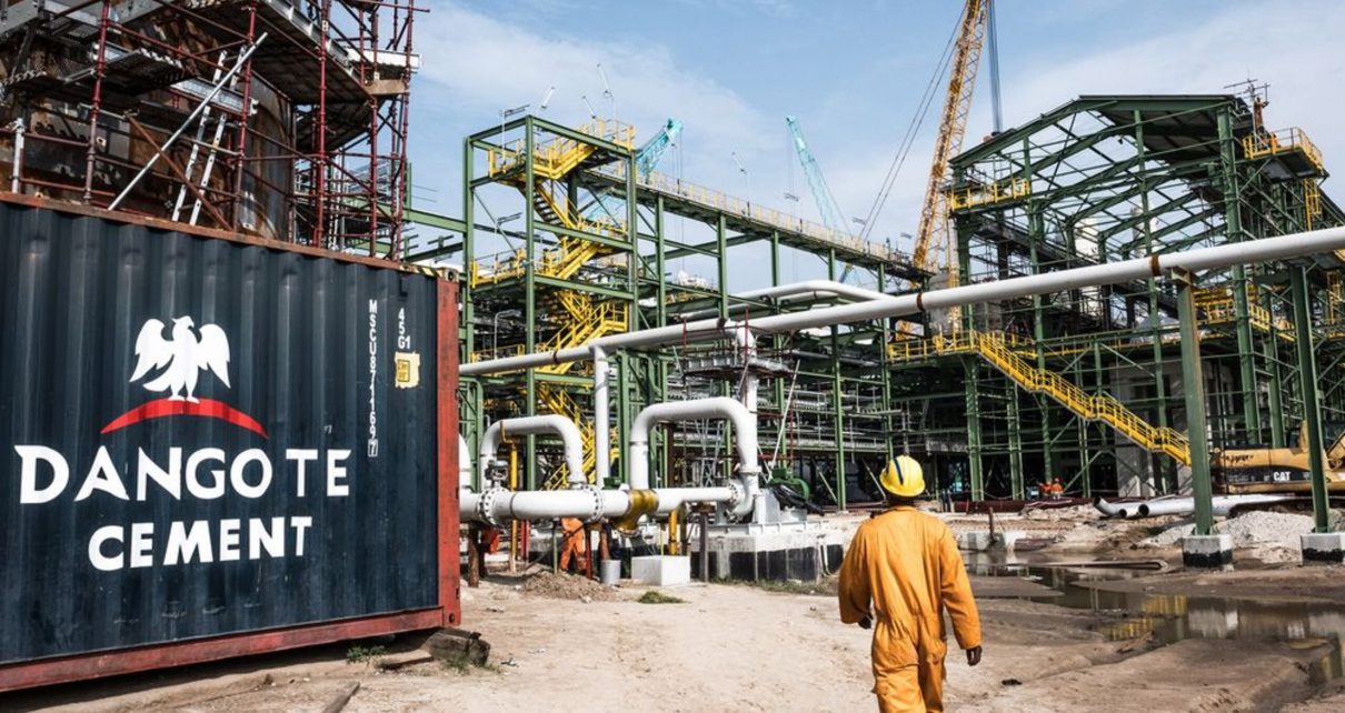 A Dangote Cement Plc logo stands on a barrier at the under-construction Dangote Industries Ltd. oil refinery and fertilizer plant site in the Ibeju Lekki district, outside of Lagos, Nigeria, on Thursday, July 5, 2018. The $10 billion refinery, set to be one of the worlds largest and process 650,000 barrels of crude a day, should be near full capacity by mid-2020, Devakumar Edwin, group executive director at Dangote Industries said in an interview.